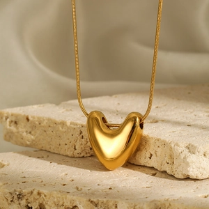 Macro detail of polished gold heart pendant necklace on textured stone background
