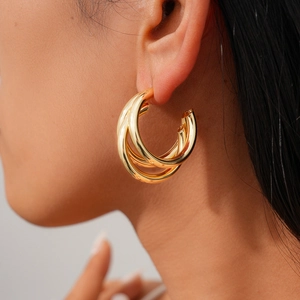 Close-up of triple-layered golden hoop earrings on model for a trendy retro fashion look