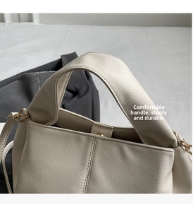 Close-up of beige leather handbag handle featuring durable pebble grain texture and metal hardware