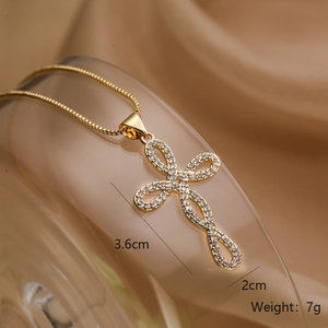 Close-up of gold-plated cross necklace with zircon stones on silk fabric, 3.6cm size