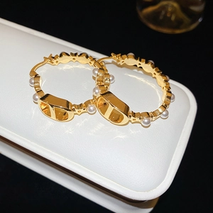 Macro shot of gold-plated hoop earrings with pearls and polished metal finish details