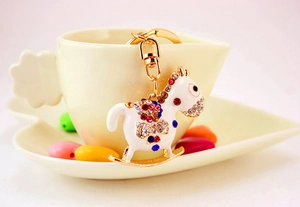 Close-up of a rocking horse keychain with colorful rhinestones and gold clasp