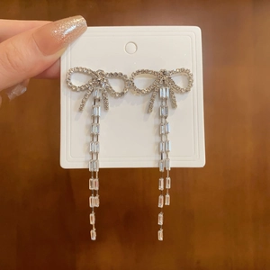 Detail of silver long tassel earrings with sparkling bow and white cubic zirconia crystals