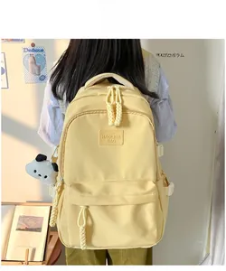 Detail view of yellow waterproof canvas backpack with side pockets and panda plush charm