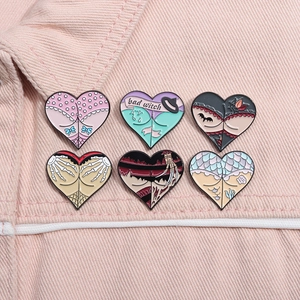 Collection of heart enamel pins with witch and goth themes on pink denim fabric