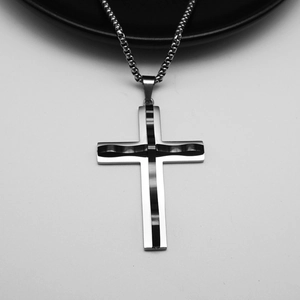 Detail of silver and black stainless steel cross pendant with box chain on grey background