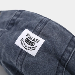 Gros plan sur la texture du denim bleu délavé et l'écusson logo Brooklyn sur le chapeau