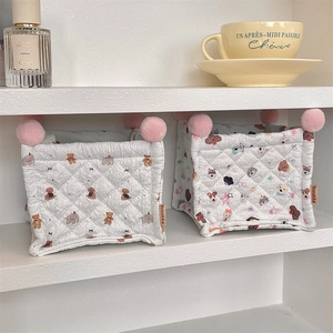Quilted cotton storage baskets with bear patterns and pink pom poms on shelves