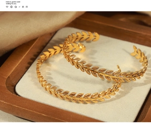 Detailed close-up of golden wheat ear texture on a stylish gold-plated open bangle