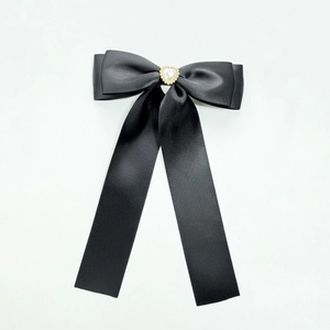Barrette à nœud en satin noir avec perle en forme de cœur sur fond blanc épuré