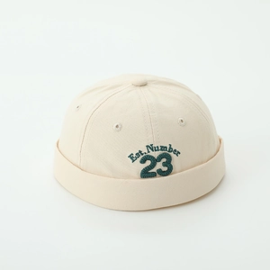 Close-up of beige Miki Hat with green Est. Number 23 embroidery on canvas texture
