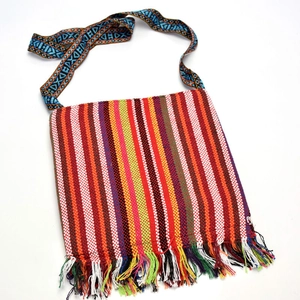 Detailed close-up of ethnic woven crossbody bag with colorful stripes and long tassels