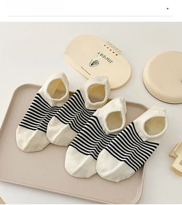 Detail of striped low-cut cotton socks set in cream and black on a minimalist tray
