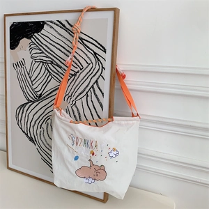 Detail of cute elephant embroidery on white canvas tote with bright orange shoulder strap