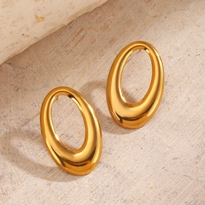 Polished gold hollow geometric oval stud earrings on a textured stone surface