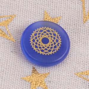 Pietra curativa in opale blu scuro con mandala dorato su sfondo in lino bianco