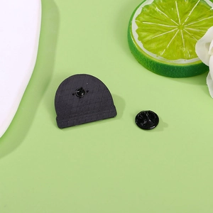 Black rabbit metal brooch and pin back accessory set for Easter on a light green background