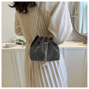 Detail showing a black bucket bag with silver rhinestones, chain strap, and pearl charms