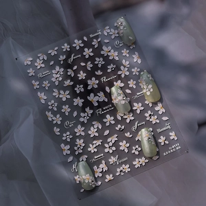 Macro detail of 3D embossed nail stickers featuring white pear blossoms and crystal accents