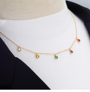 Close-up of gold chain necklace with five colorful round gemstone pendants on a mannequin