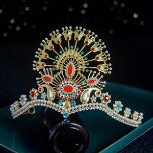 Detailed close-up of a gold bridal crown with red gemstones, pearls, and blue accents