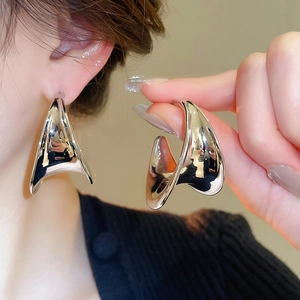 Macro shot of silver C-shaped chunky earrings with polished liquid metal finish