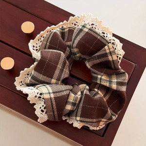 Close-up of brown plaid scrunchie with delicate beige lace trim and retro fabric texture
