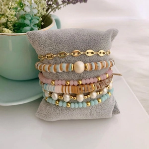 Detail of stacked bohemian bracelets with pearls and clay beads on a jewelry pillow