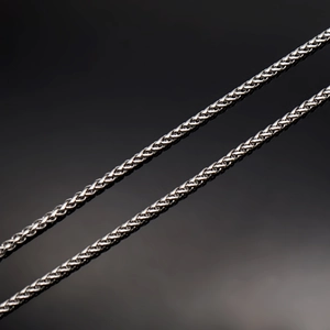 Gros plan sur la chaîne en acier inoxydable montrant la texture tressée et l'éclat argenté