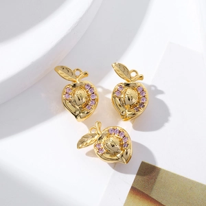 Detailed close-up of 18K gold-plated peach pendants with pink cubic zirconia inlays
