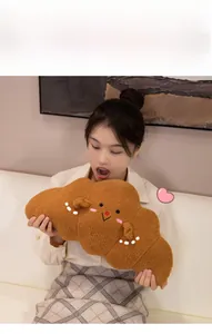 Detail of soft croissant plush pillow with cute embroidered face held by a model