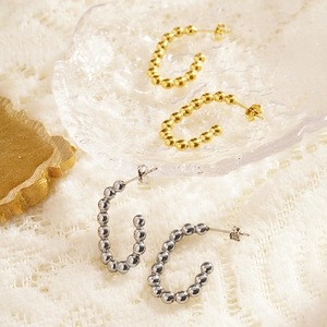 Minimalist gold and silver beaded C-shape hoop earrings on elegant white lace