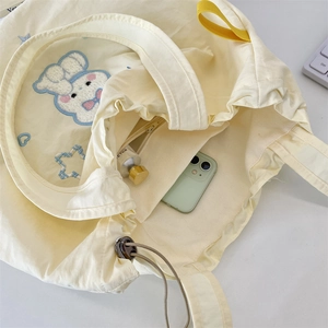 Detail of yellow canvas tote bag showing interior zipper pocket and cute rabbit embroidery