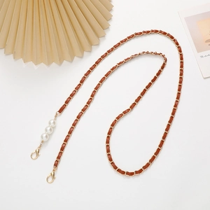 Detail of gold metal and brown leather woven phone strap with three white pearls and clasps
