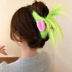 Green plush monster hair claw clip with pink ears shown on brown hair bun style