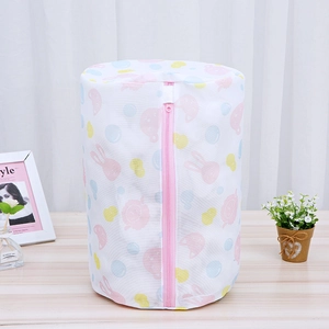 Detail view of cylindrical mesh laundry bag with cute rabbit prints on a wooden surface