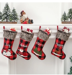 Détail de quatre chaussettes de Noël à carreaux buffalo avec bordure en fourrure sur la cheminée