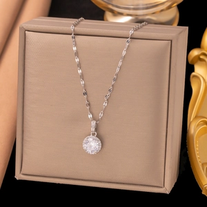 Collier goutte d'eau argenté avec pendentif rond en zircone posé sur un coffret cadeau