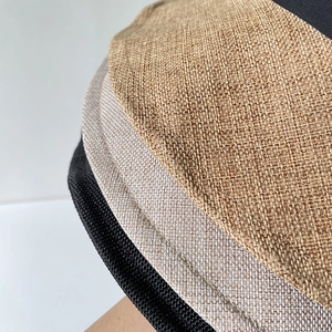 Dettaglio della trama in lino e cuciture su cappelli parasole impilati multicolore