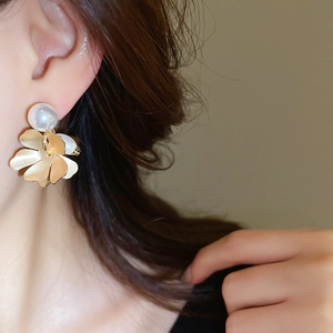 On-ear view of golden flower earrings with matte petals and white freshwater pearl