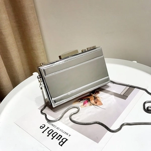 Détail de la pochette rectangulaire argentée avec bandoulière chaîne sur table