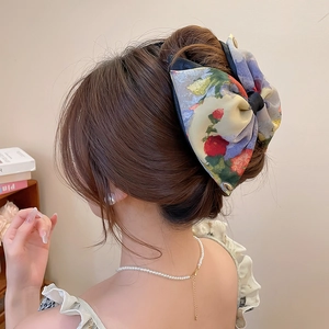 Floral print fabric bow hair clip shown on elegant bun with vintage style detail