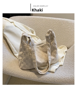 Detail of khaki woven checkerboard tote bag texture on a cozy cream-colored chair