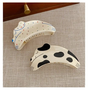 Detailed view of acetate hair claws featuring colorful polka dots and cow print patterns