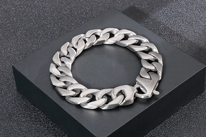 Gros plan d'un bracelet gourmette lourd pour homme en acier inoxydable finition argent mat
