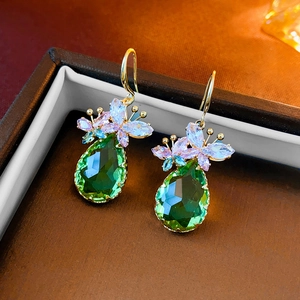 Detail of gold drop earrings with green waterdrop gemstone and colorful flower zircon studs