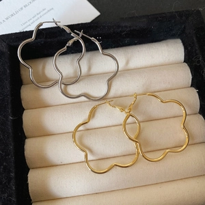 Minimalist flower-shaped wavy hoop earrings in gold and silver finish set on a display box
