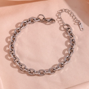Macro detail of 18K silver stainless steel chain anklet showing lobster clasp and link texture