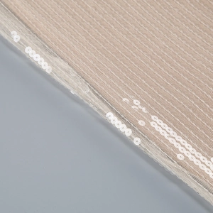 Close-up of champagne sequin embroidery on mesh fabric for a luxury evening dress