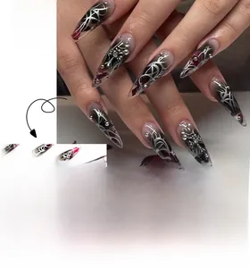 Detail of long stiletto press-on nails with black red gradient and silver metal decor